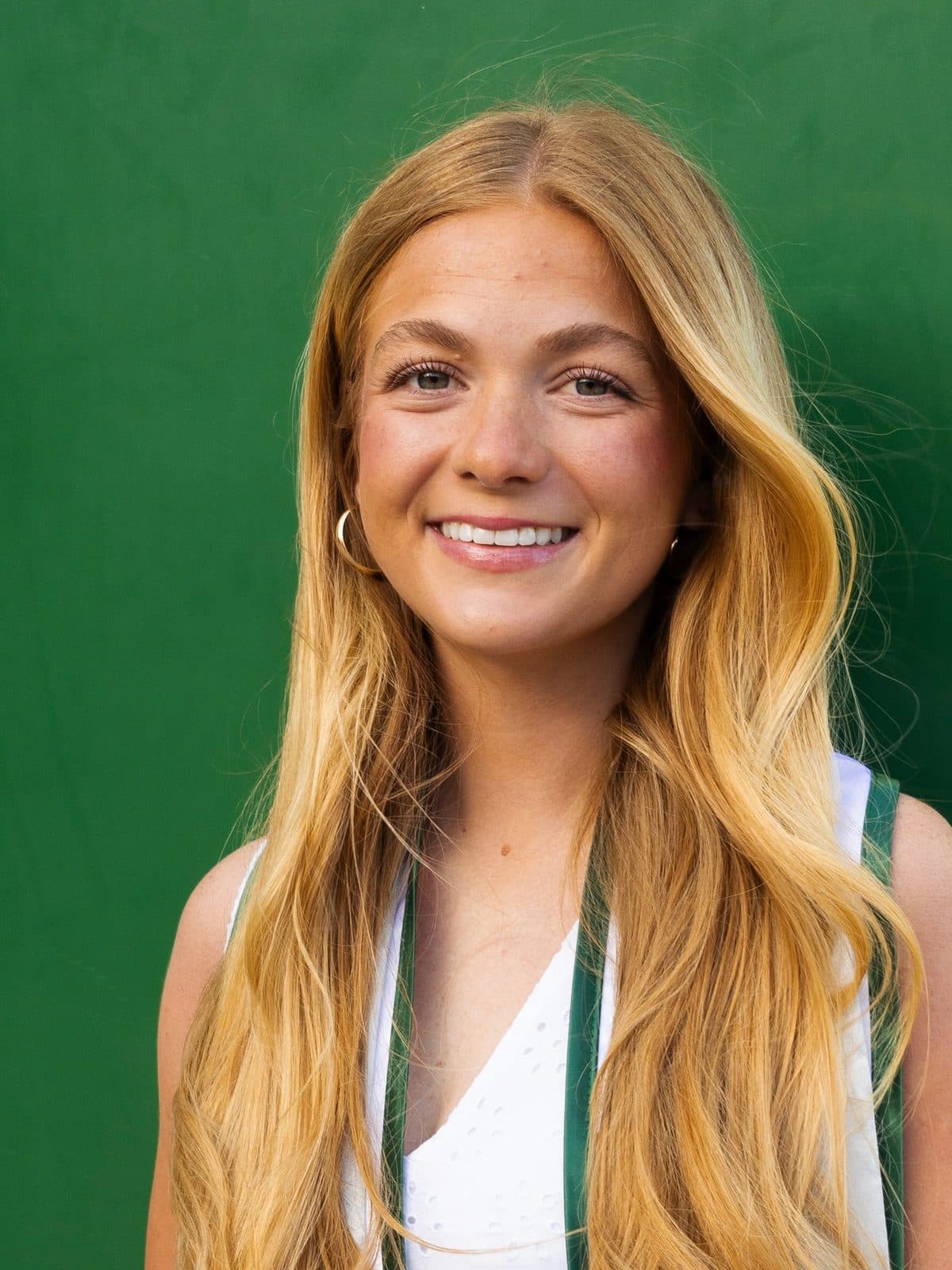 Kate Iverson smiling outdoors in front of a green wall